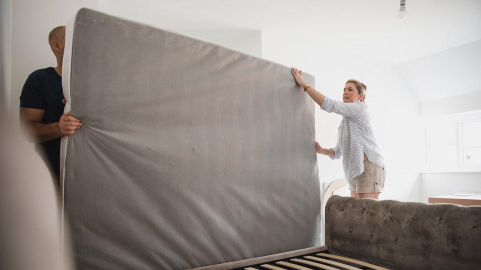 Mature couple are setting up their bed in their new home.