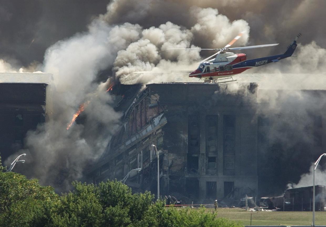 <span>A rescue helicopter surveys damage to the Pentagon as firefighters battle flames after an airplane crashed into it on 11 September 2001.</span><span>Photograph: Larry Downing/Reuters</span>