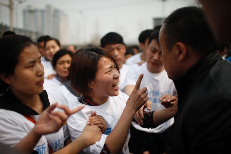 A relative of a passengers on missing Malaysia Airlines flight MH370 yells at a security guard during a protest outside the Malaysian embassy in Beijing, on March 25, 2014