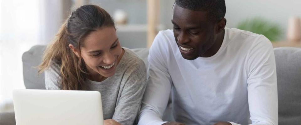 Happy mixed race young couple calculate domestic bills mortgage rates