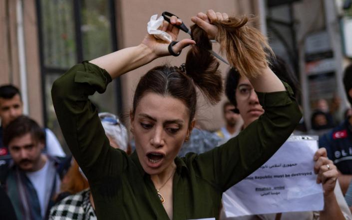 An Iranian expat cuts off her hair in a protest outside Tehran's consulate in Istanbul - YASIN AKGUL /AFP/Getty