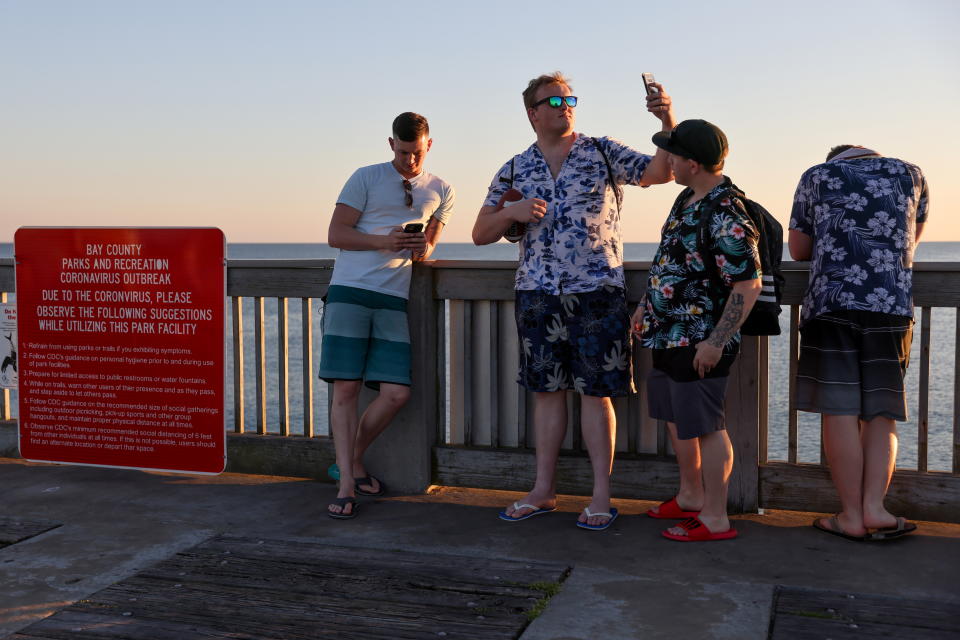 Young men enjoy the view from the pier as the sun begins to set on families and spring breakers amid the coronavirus disease (COVID-19) outbreak in Panama City Beach, Florida, U.S. March 7, 2021.  REUTERS/Jonathan Ernst