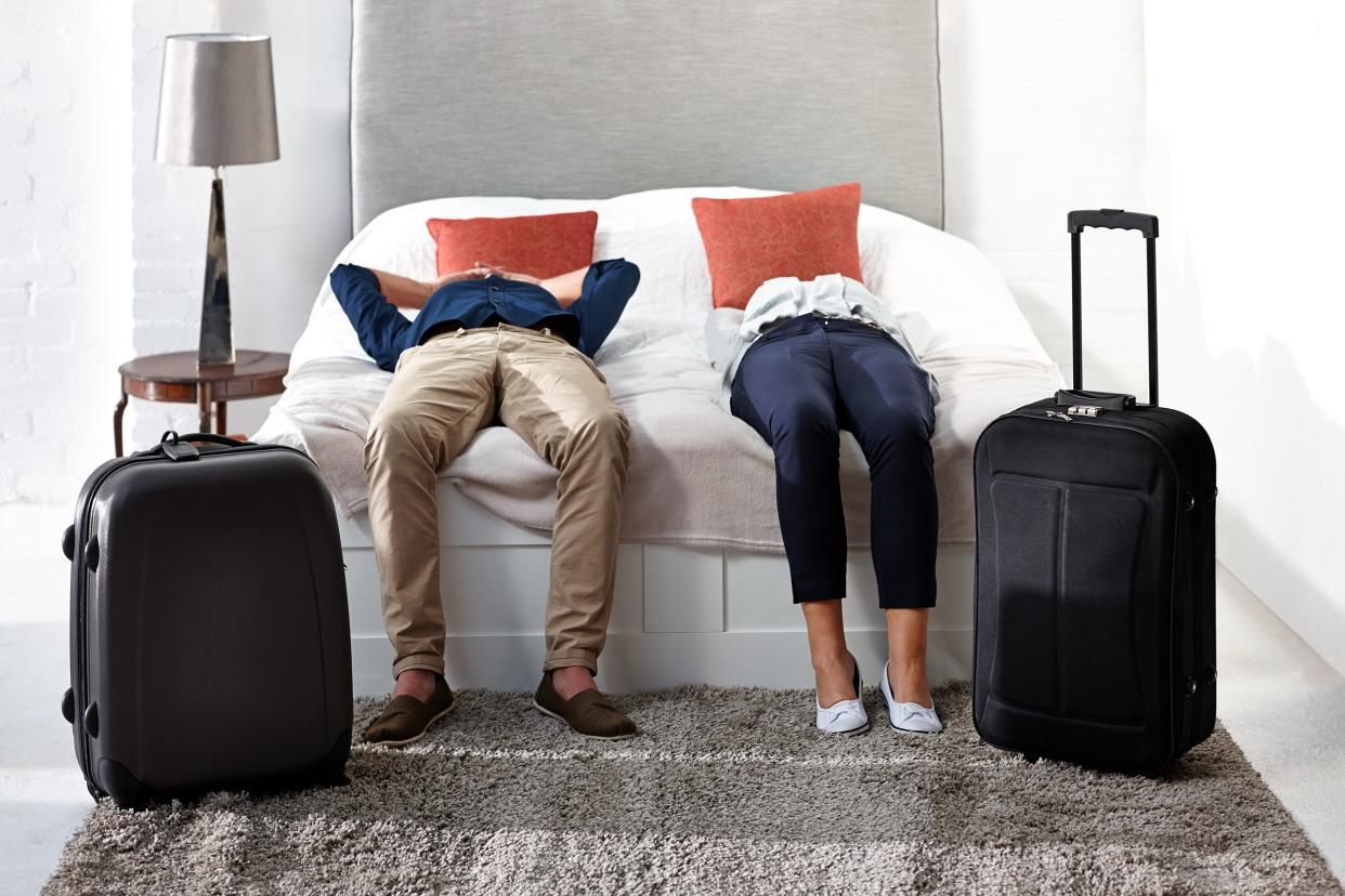 Exhausted couple arriving at hotel and lying on the bed