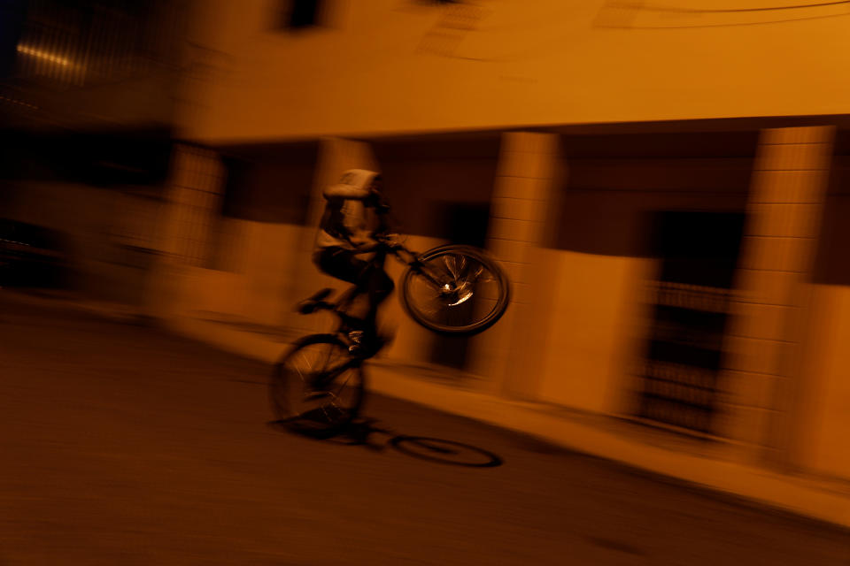 A boy rides a bicycle on a street in Cova da Moura