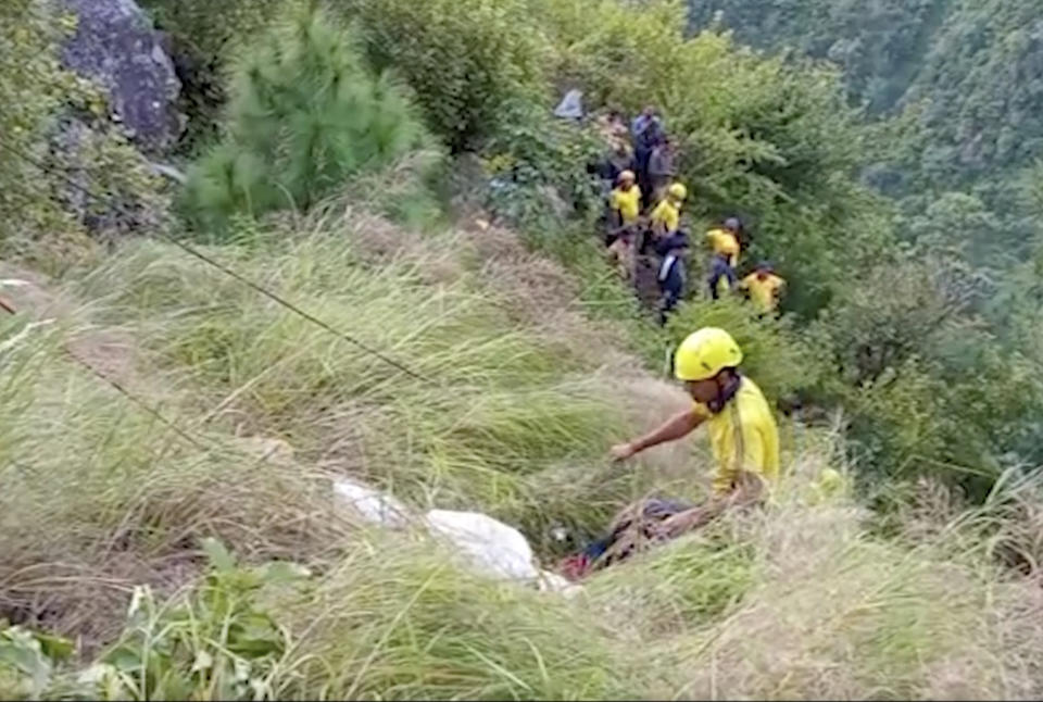 In this grab made from video provided by KK Productions, rescuers pull a body of passenger from a bus that fell into a gorge in Pauri district in the northern state of Uttarakhand, India, Wednesday, Oct. 5, 2022. A bus in northern India plunged into a gorge, leaving at least 25 dead and 20 others injured, officials said. (KK Productions via AP)