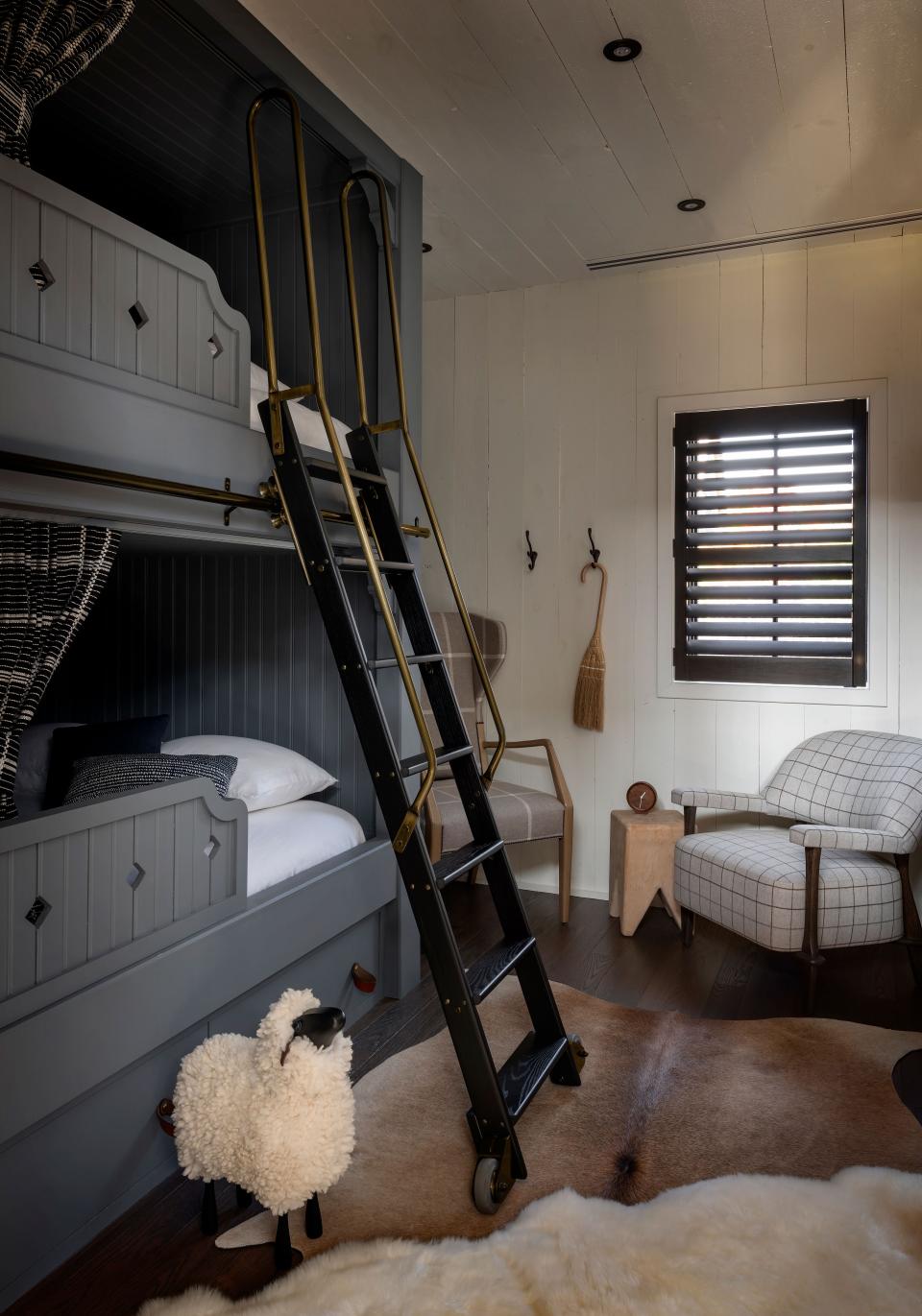 These bunk beds are not necessarily for kids; they are actually queen-size and designed for adult overnight guests. The black ash and antique brass ladder is from Alaco Ladder Company, the hide rug is by Vaheed Taheri, and the armchair is by Gregorius Pineo.