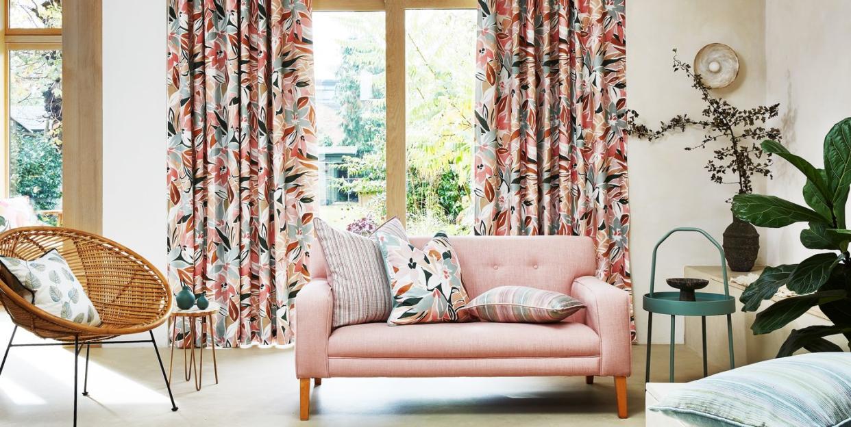 a living room with a pink couch and floral curtains