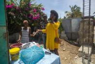 Semi Kaefra Alisha Fermond,m una mujer transexual, paga a una vendedora ambulante por una pizza creole, en Puerto Príncipe, Haití, el 15 de agosto de 2020. “Estoy orgullosa de mí misma porque ahora puedo vestir ropa de mujer e ir a todas partes", afirmó. “En la casa de mi madre no puedo ser así”. (AP Foto/Dieu Nalio Chery)