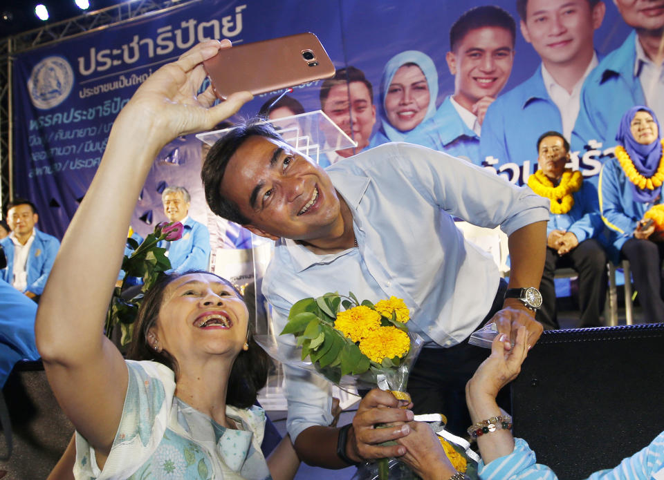 In this Monday, March 18, 2019. a supporter takes a selfie with the leader of Thailand's Democrat Party Abhisit Vejjajiva during an election campaign in Bangkok, Thailand. Abhisit says if he becomes prime minister after Sunday’s election, he’ll make careful but forceful efforts to undo undemocratic constitutional clauses imposed by the military government that took power in 2014. (AP Photo/Sakchai Lalit)