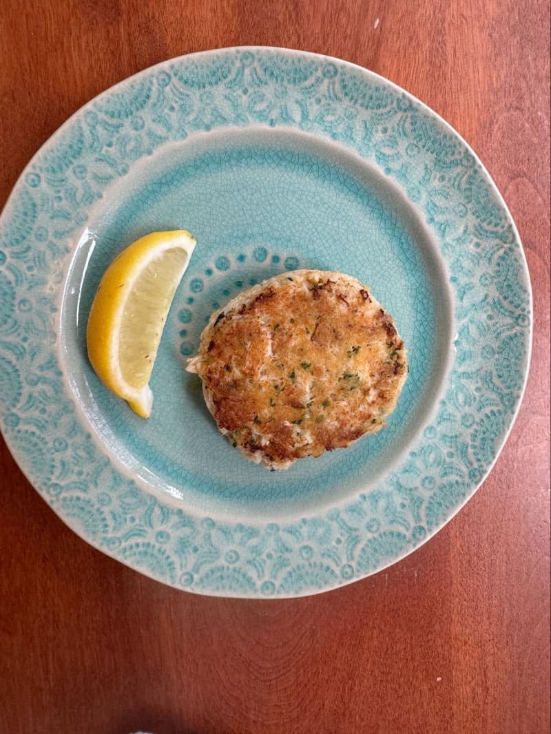 Crab cake on plate with side of lemon.