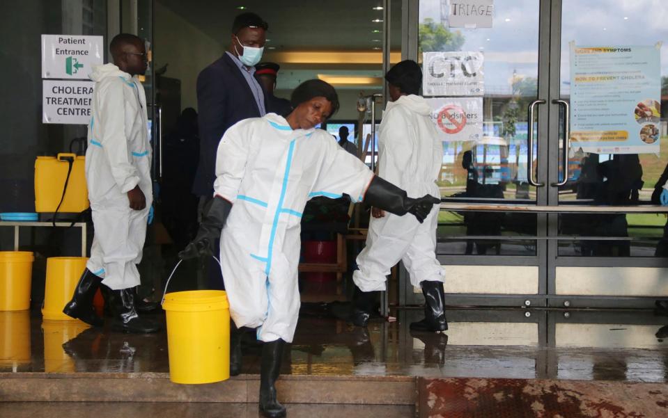 A worker carries a bucketfull of disinfectant at a cholera treatment centre, in Lusaka, Zambia