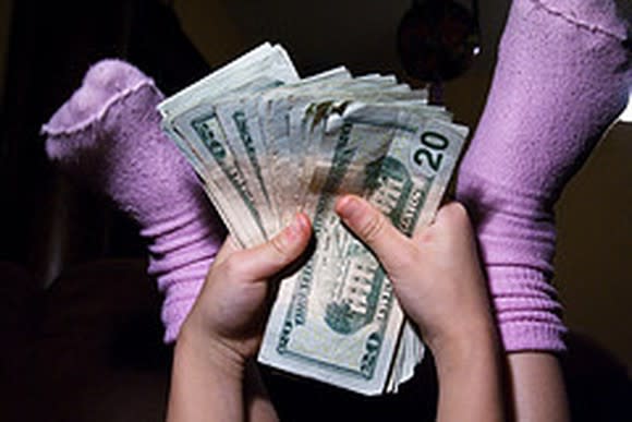 Close up picture of a persons stocking feet with handfuls of cash.