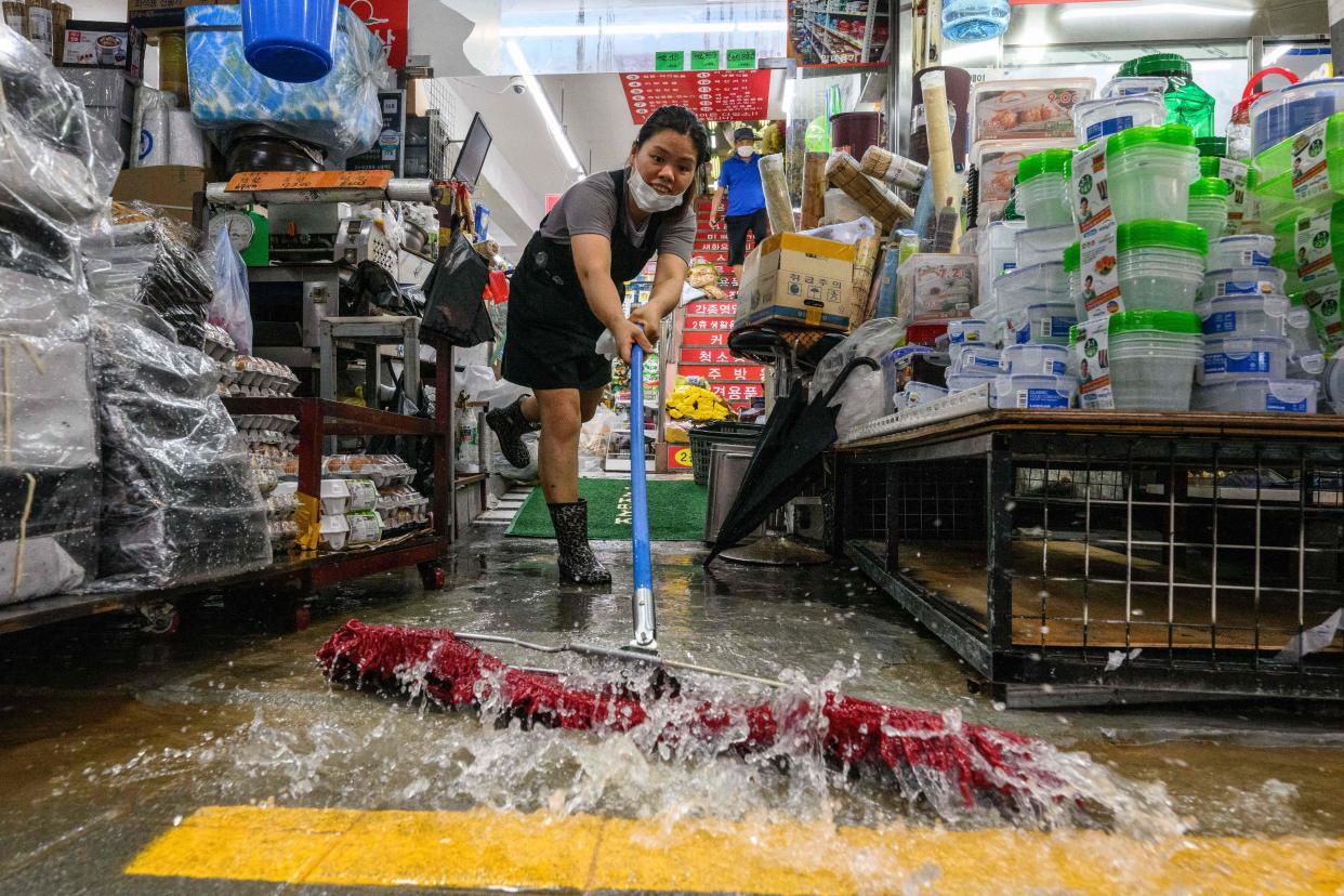 A worker clears water from her shop at the historic Namseong Market in the Gangnam district of Seoul on Tuesday. 