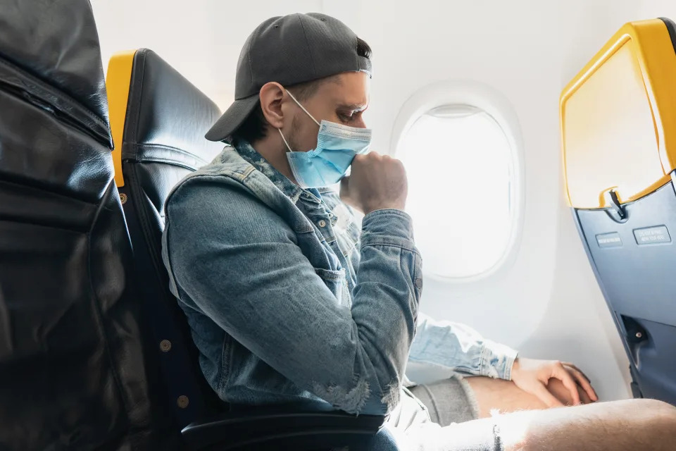 Young man traveler wearing prevention mask during a flight inside an airplane