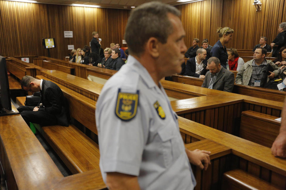 Oscar Pistorius, left, sits in the dock in court in Pretoria, South Africa, Friday, March 14, 2014 prior to the tenth day of his murder trial proceedings. Pistorius is charged with the shooting death of his girlfriend Reeva Steenkamp, on Valentines Day in 2013. (AP Photo/Kim Ludbrook, Pool)