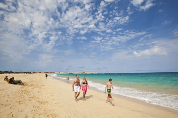 SAL REI, CAPE VERDE - MAY 15:  People walk on the beach at Santa Maria on May 15, 2012 in Sal Rei, Cape Verde. Favorable exchange rates in the Cape Verde Islands have recently attracted foreign investors, especially from the UK, with an increase in tourism, retail and property investments.  (Photo by Michel Porro/Getty Images)