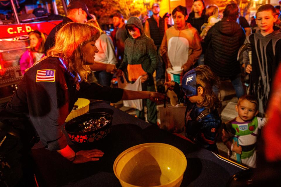 Hanna Miller, a member of the Columbia Fire Department, hands out candy to trick or treaters during Haunting in the District in Columbia, Tenn. on Oct. 31, 2022.