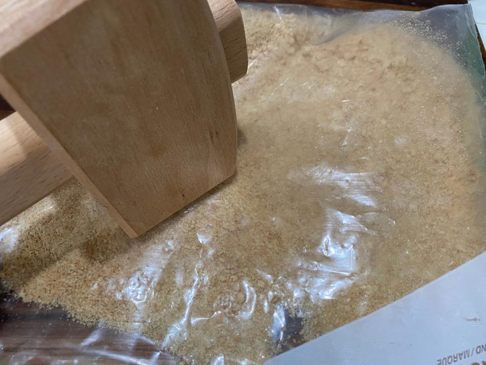 Smashing graham crackers under plastic wrap with a mallet