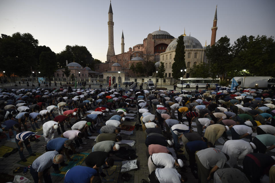 Muslims offer their evening prayers outside the Byzantine-era Hagia Sophia, one of Istanbul's main tourist attractions in the historic Sultanahmet district of Istanbul, following Turkey's Council of State's decision, Friday, July 10, 2020. Turkey's highest administrative court issued a ruling Friday that paves the way for the government to convert Hagia Sophia - a former cathedral-turned-mosque that now serves as a museum - back into a Muslim house of worship. The Council of State threw its weight behind a petition brought by a religious group and annulled a 1934 cabinet decision that changed the 6th century building into a museum. (AP Photo/Emrah Gurel)