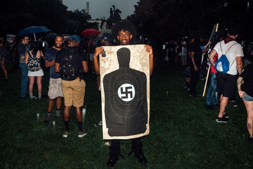 A counter-protester holds a shooting target with a swastika in the middle.