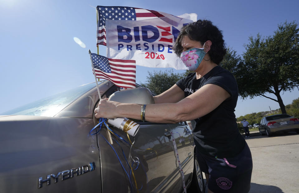 Ann Grannan puts a flag on her car before a Ridin' With Biden event Sunday, Oct. 11, 2020, in Plano, Texas. Democrats in Texas are pressing Joe Biden to make a harder run at Texas with less than three weeks until Election Day. (AP Photo/LM Otero)