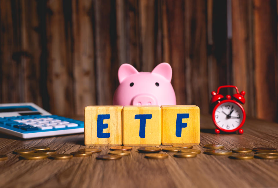 The word ETF from Exchange Traded Fund written in English language on wooden cubes. An alarm clock, calculator and coins in the composition. Economy and investment concepts.