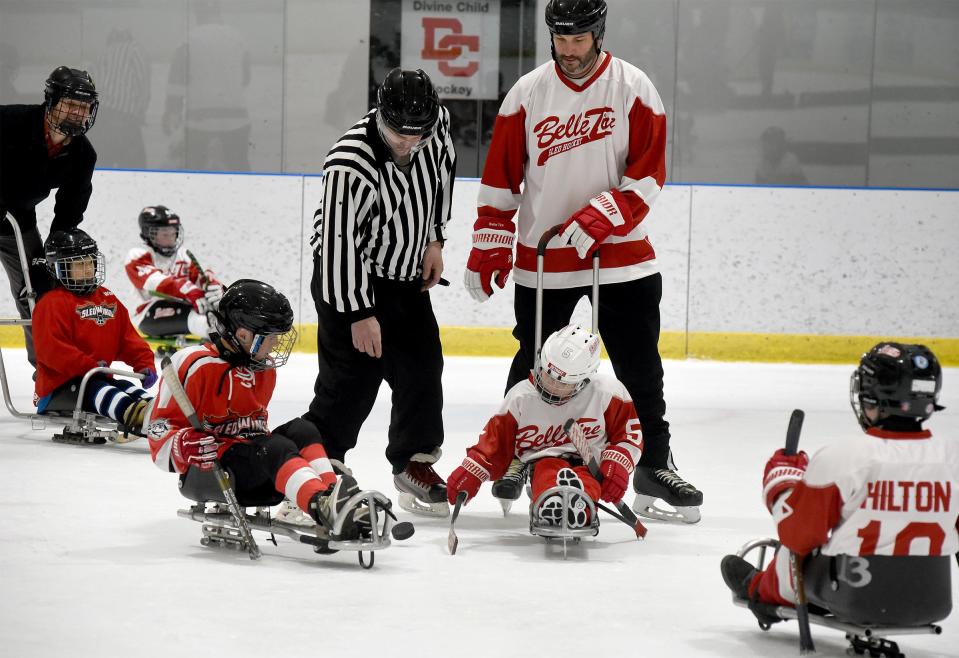 The puck is dropped as Conner Adcock, 9, (right center) of the Belle Tire Sled Hockey team attempts to hit the puck with his dad Steve Adcock watching in the recent tournament Jan. 20, 2024 at Taylor Sportplex.