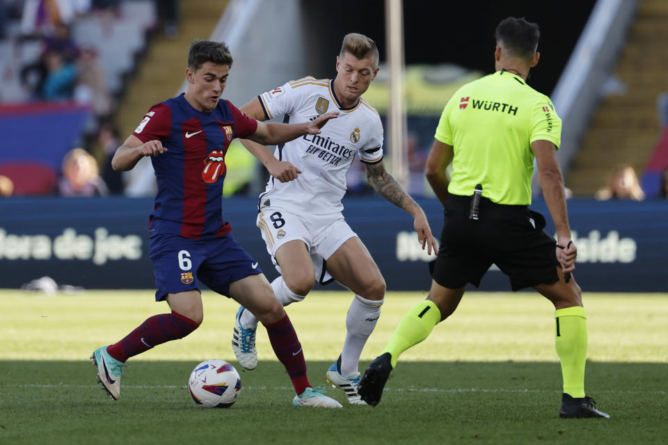 Barcelona's Gavi, left, challenges for the ball with Real Madrid's Toni Kroos during the La Liga soccer match between Barcelona and Real Madrid at the Olympic Stadium in Barcelona, Spain, Saturday, Oct. 28, 2023. (AP Photo/Joan Monfort)