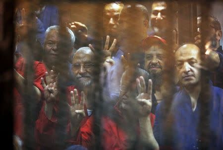 Mohamed Badie (2nd L), general guide of the Muslim Brotherhood, and other Muslim Brotherhood members gesture behind bars after their verdict at a court at the outskirts of Cairo, Egypt June 16, 2015. REUTERS/Asmaa Waguih