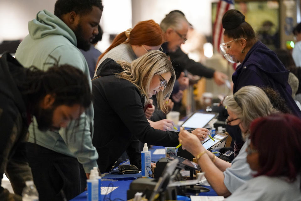 FILE - People check in to cast their votes at a polling station in a mall Nov. 8, 2022, in Las Vegas. Republicans are re-evaluating their antipathy to mail voting. After former President Donald Trump condemned that method of casting ballots in 2020, conservatives shied away from it. That's given Democrats a multiweek jump on voting during elections. (AP Photo/Gregory Bull, File)