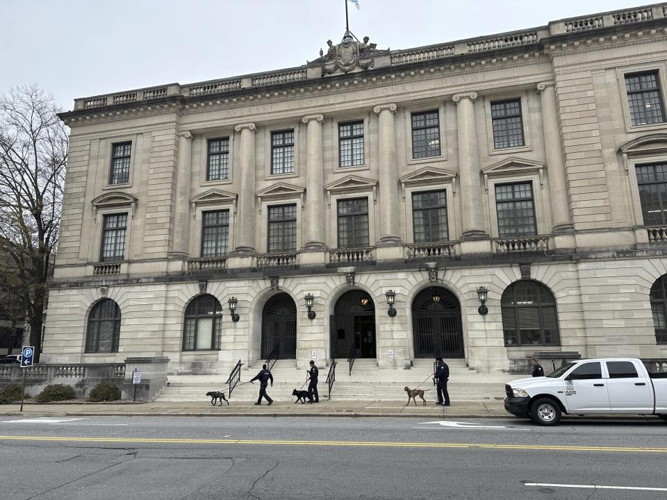 Police dogs sniff the outside of the Pulaski County courthouse in downtown Little Rock, Ark., on Thursday, Jan. 4, 2024. The courthouse was evacuated after a bomb threat was received, and police allowed the public to re-enter later that morning. The evacuation delayed the start of a court hearing in the legal fight between the state Board of Corrections and Gov. Sarah Huckabee Sanders over who runs the state prison system. (AP Photo/Andrew DeMillo)