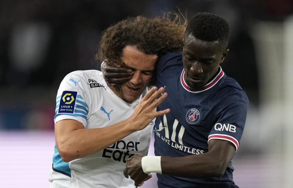 Marseille's Matteo Guendouzi, left, duels for the ball with PSG's Idrissa Gueye during the League One soccer match between Paris Saint Germain and Marseille, at the Parc des Princes stadium, in Paris, France, Sunday, April 17, 2022. (AP Photo/Francois Mori)