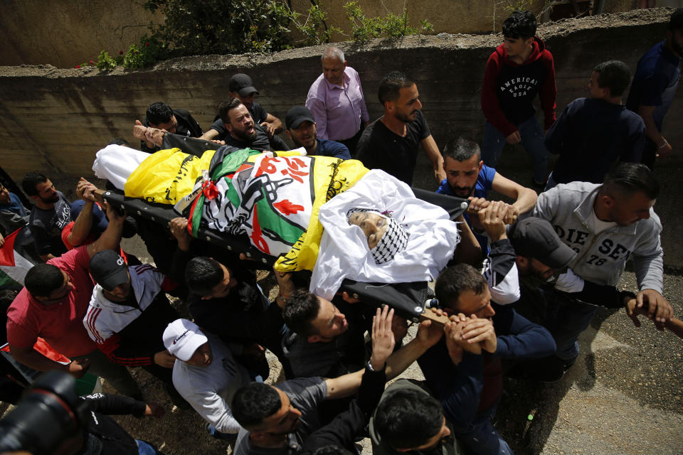 FILE - In this April 6, 2021 file photo, Palestinians carry the body of Osama Mansour who was killed by Israel soldiers at a temporary vehicle checkpoint in the occupied West Bank near Jerusalem, during his funeral, in the village of Biddu near the West Bank city of Ramallah. Somaya, Mansour's wife, who was in the car with her husband and was wounded by the gunfire, said they followed the soldiers' instructions and posed no threat. The shooting death has revived criticism of the Israeli military's use of deadly force. (AP Photo/Majdi Mohammed, File)