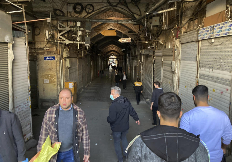 People walk through closed shops of Tehran's Grand Bazaar, Iran, Tuesday, Nov. 15, 2022. Many shops at Grand Bazaar in Iran's capital city were closed Tuesday amid strike calls following the September death of a woman who was arrested by the country's morality police. (AP Photo/Vahid Salemi)