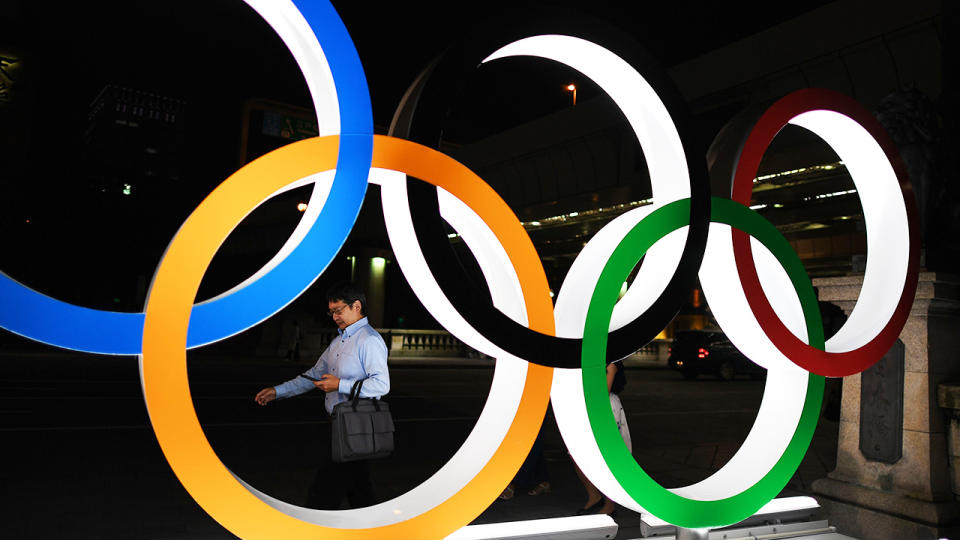 A man, pictured here walking in front of the Olympic Rings in Tokyo.