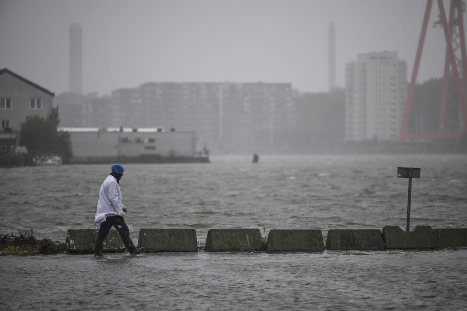 A man walks along a flooded Fiskhamnen (fishing port) after the Gota Alv river overflowed after heavy raining in Gothenburg, Sweden, Tuesday, Aug. 8, 2023. (Björn Larsson Rosvall/TT News Agency via AP)