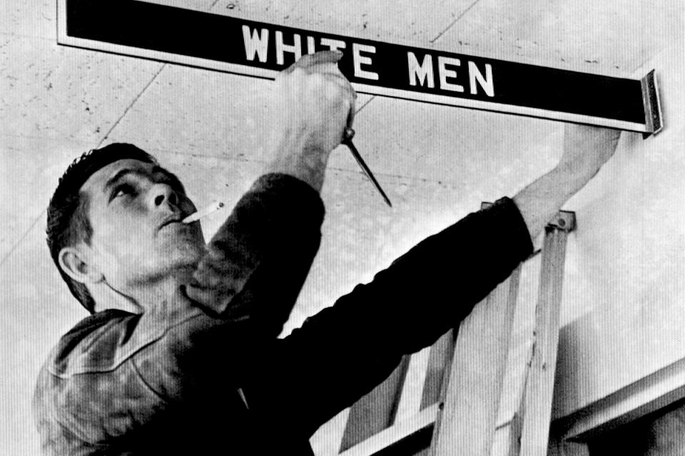 FILE - A workman removes a restroom sign at Montgomery Municipal Airport, Jan. 5, 1962, in compliance with a federal court order banning segregation. However, city officials delayed plans to remove waiting room furniture and close toilets and water fountains. But they said these and the airport restaurant will be closed if there is a concerted integration attempt. (AP Photo/File)