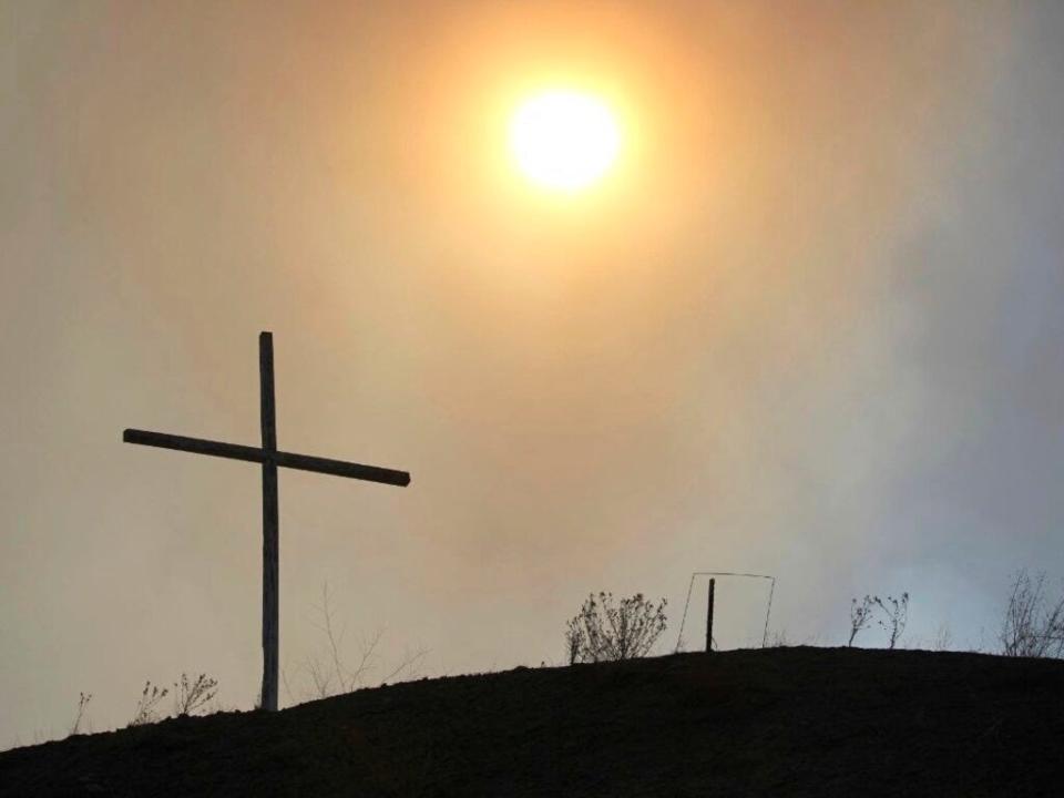 This May 4, 2022 image courtesy of Laura Paskus shows the silhouette of a cross amid smokey skies where hundreds of firefighters are battling a massive wildfire burning in the Sangre de Cristo Mountains near the community of Las Vegas, New Mexico.