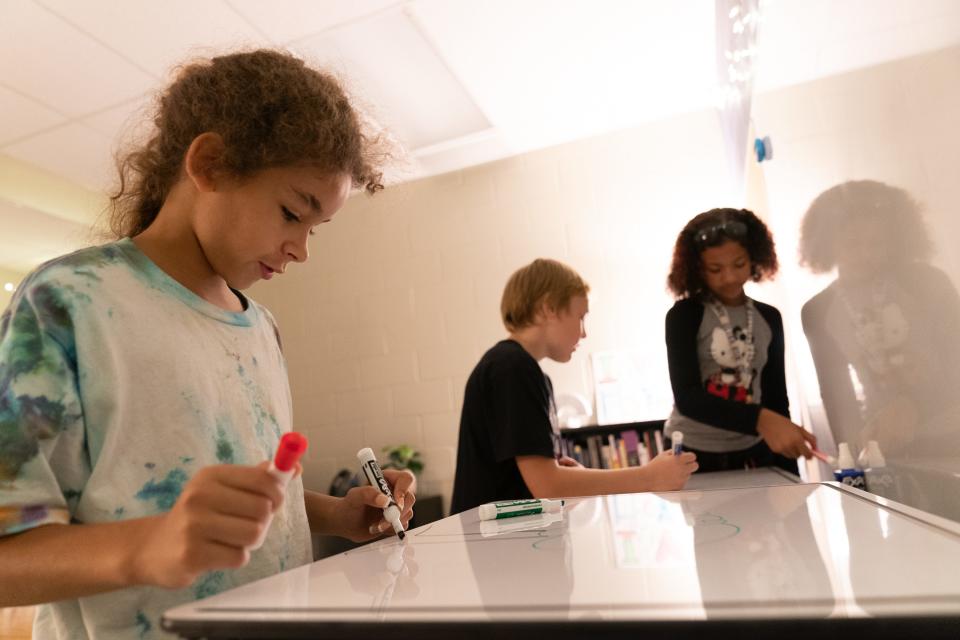 Ross Elementary fourth-graders, from left, Zara Douglas, Caius Bonsall and Eve Socia show how the standing desks help them to stay on task in counselor Eva Yerkes' room.