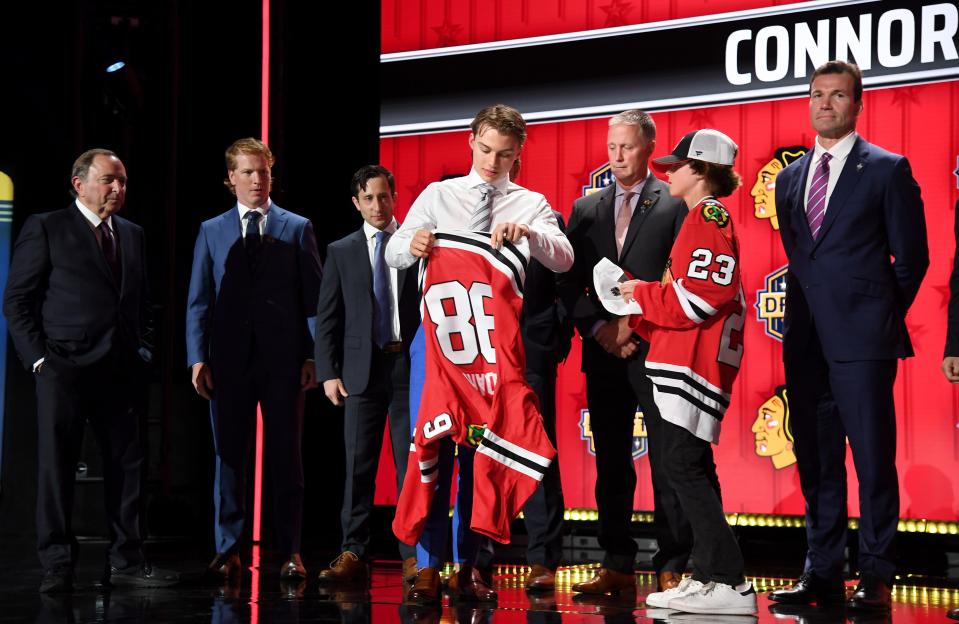 Connor Bedard puts on a Chicago Blackhawks jersey after being taken with the first pick in the 2023 NHL draft.