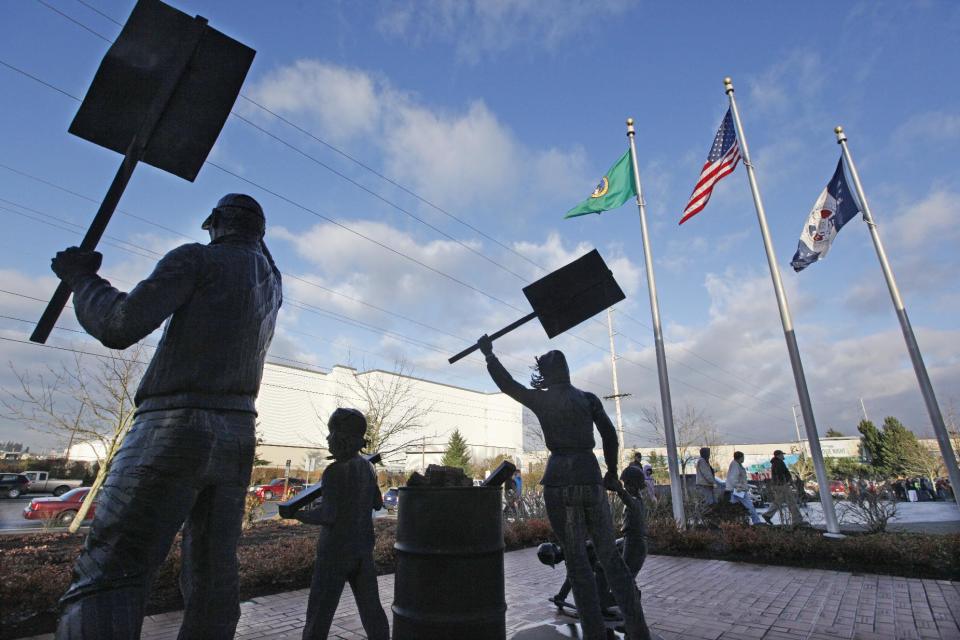 Boeing machinists walk past statues commemorating striking workers as they prepare to vote at their union hall Friday, Jan. 3, 2014, in Everett, Wash. The vote will determine Friday whether Boeing machinists will accept a contract that would concede some pension and health care benefits in order to secure assembly of the company's new 777X airplane in Washington state. (AP Photo/Elaine Thompson)