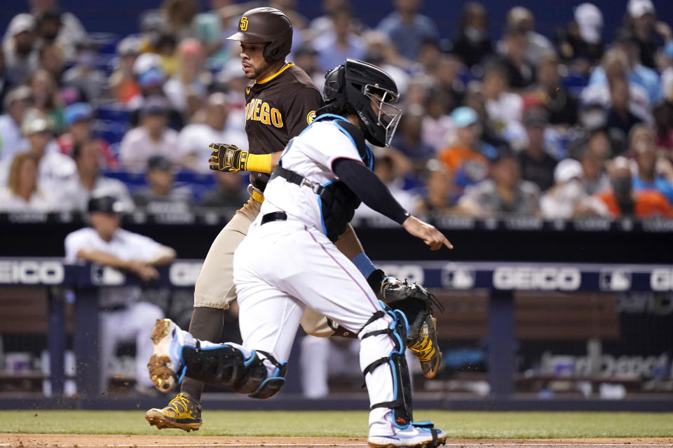 San Diego Padres' Tommy Pham, left, scores past Miami Marlins catcher Jorge Alfaro on a single hit by Jurickson Profar during the fourth inning of a baseball game, Thursday, July 22, 2021, in Miami. (AP Photo/Lynne Sladky)