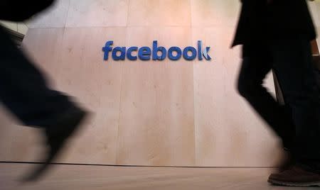 People walk in front of the Facebook logo at the new Facebook Innovation Hub during a preview media tour in Berlin, Germany, February 24, 2016. REUTERS/Fabrizio Bensch