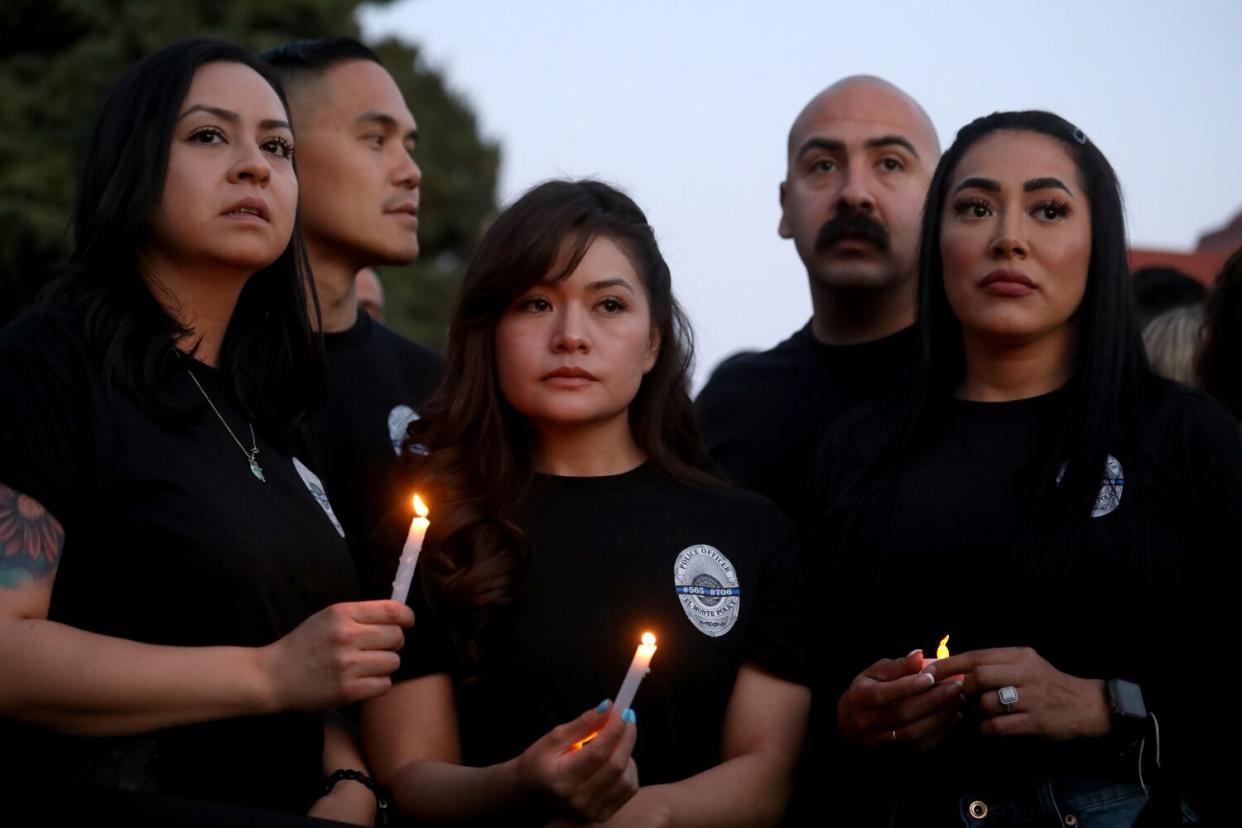 Three women and two men, some holding candles, at the vigil