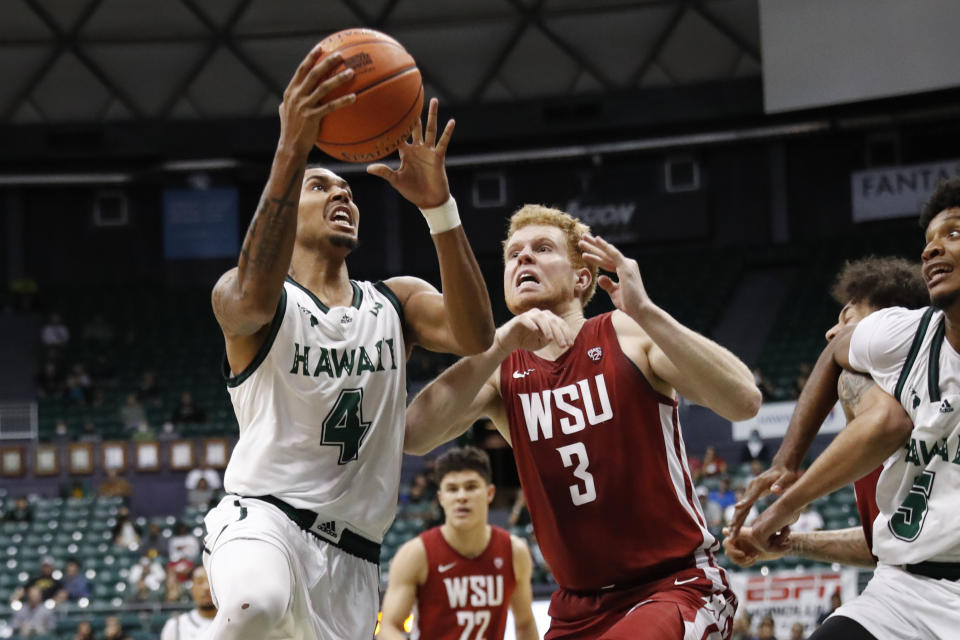 Hawaii guard Noel Coleman (4) goes up for a layup over Washington State guard Jabe Mullins (3) during the second half of an NCAA college basketball game, Friday, Dec. 23, 2022, in Honolulu. (AP Photo/Marco Garcia)