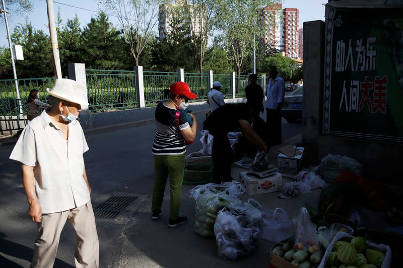 People buy vegetables and fruits at a street stall near a residential area in Beijing