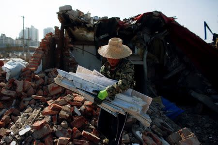 Migrant worker Wang Jun carries scrap material she collects from debris of demolished buildings to sell at recycling yards at the outskirts of Beijing, China October 1, 2017. Picture taken October 1, 2017. REUTERS/Thomas Peter