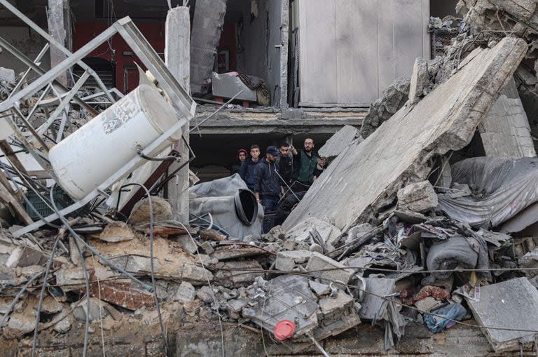 Palestinos buscan entre los escombros de su casa, la cual fue destruida en un ataque aéreo israelí durante la noche en el campamento de refugiados de Rafah, en el sur de la Franja de Gaza, el 27 de febrero de 2024.