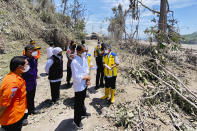 In this photo released by Indonesian Presidential Palace, Indonesian President Joko Widodo, center, inspects an area covered in ash from the eruption of Mount Semeru in Lumajang district, East Java province, Indonesia, Tuesday, Dec. 7, 2021. Widodo visited areas devastated by the powerful volcanic eruption that killed a number of people and left thousands homeless, and vowed that communities would be quickly rebuilt. (Indonesian Presidential Palace via AP)