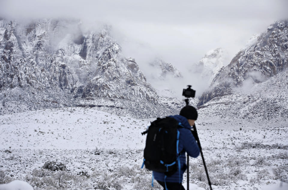 Tomek Pleskaczynski moves his camera while taking pictures during a winter storm at Red Rock National Conservation Area, Thursday, Feb. 21, 2019, near Las Vegas. (AP Photo/John Locher)